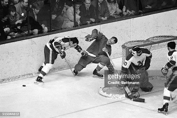 Red Wing Gordie Howe really isn't trying to decapitate Minnesota's Leo Boivan in this bit of action behind the North Stars' net during the 3/8...