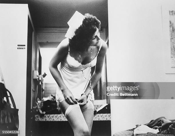 Actress Linda Lovelace dressed as a nurse and adjusting her stockings in the 1972 pornographic film Deep Throat.
