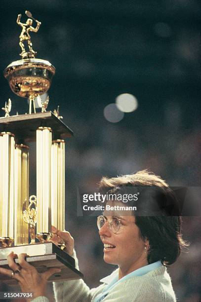 Tennis pro Billie Jean King holds her newly won trophy high after beating Bobby Riggs in their $100,000 winner take all "Battle of the Sexes" tennis...
