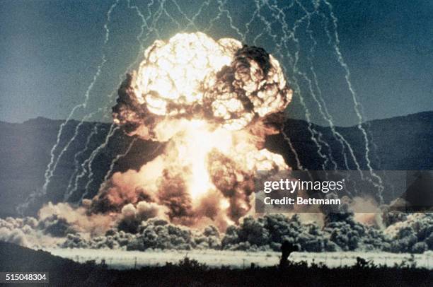 Ground level view of a surface test of a nuclear device. Slide shows the beginning of a mushroom cloud, glowing intensly white, with lightning arcing...