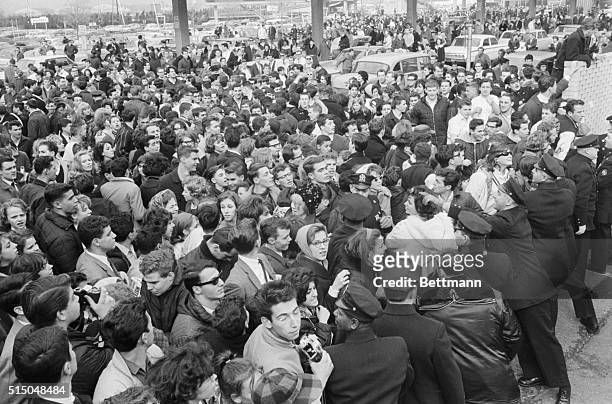 New York City police officers try their best to contain several hundred Beatles fans who have arrived at Idlewild Airport, some from hundreds of...