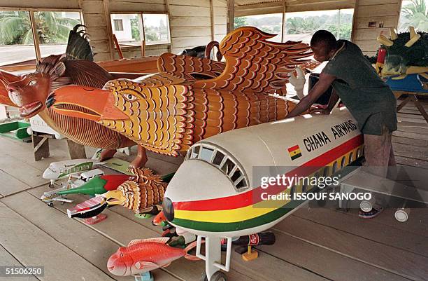 Employee of the Tchadio workshop prepares coffins representing a plane and animals 12 December 2000, in the Teshie area of Accra. Eagles, cows,...