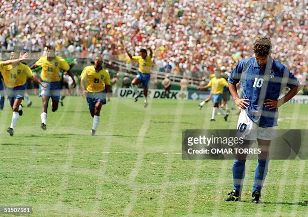 Brazilian players run to join their teammates as Italian midfielder Roberto Baggio bows his head after he missed his penalty kick giving Brazil a 3-2...