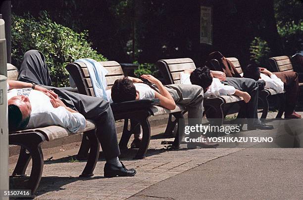 Japanese businessmen take naps on benches in Hibiya park, central Tokyo, 04 August 1994.