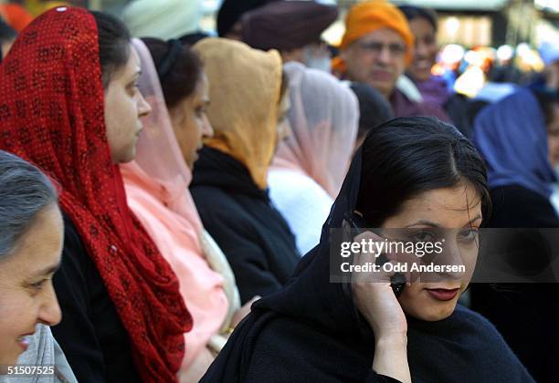 Sikh woman speaks on her cellphone surrounded by traditionally dressed woman, in the London suburb of Southall, 08 April 2001. Thousands of...