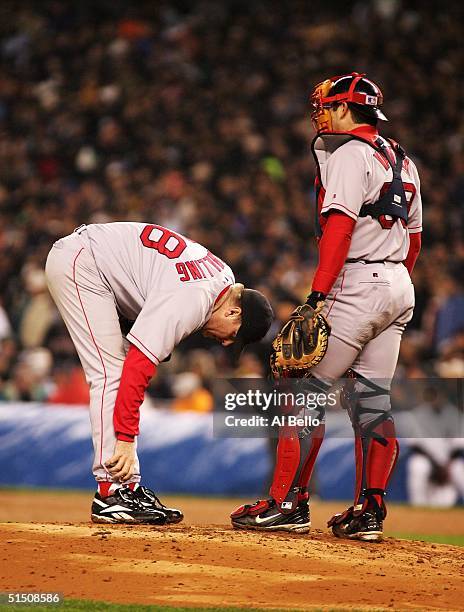 Catcher Jason Varitek of the Boston Red Sox approaches the mound as pitcher Curt Schilling looks at his ankle during game six of the American League...