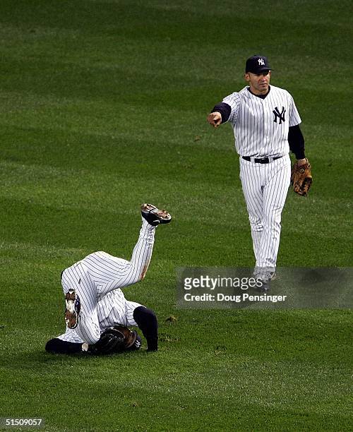 Miguel Cairo of the New York Yankees points to teammate Gary Sheffield who makes a diving catch on a fly-ball hit by Mark Bellhorn of the Boston Red...