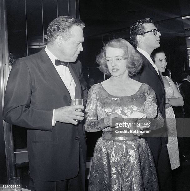 Actress Bette Davis and actor Van Heflin pause in the whirl of activity in the Rainbow Room, atop the RCA Building here. They helped celebrate the...