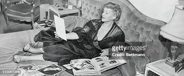 Updating her scrapbook while lying in bed is Mama Jolie Gabor, the mother of Zsa Zsa, Eva, and Magda, the famous Gabor sisters.