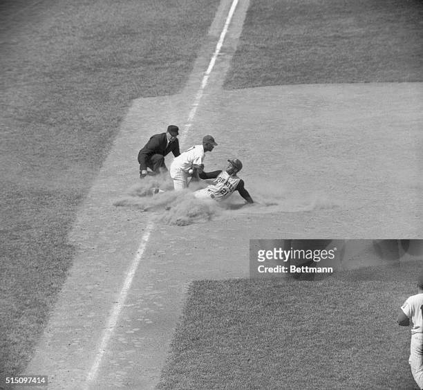 Pittsburgh's Roberto Clemente slides safely into third base in a cloud of dust after traveling from first on a hit by Wilver Stargell to right field...