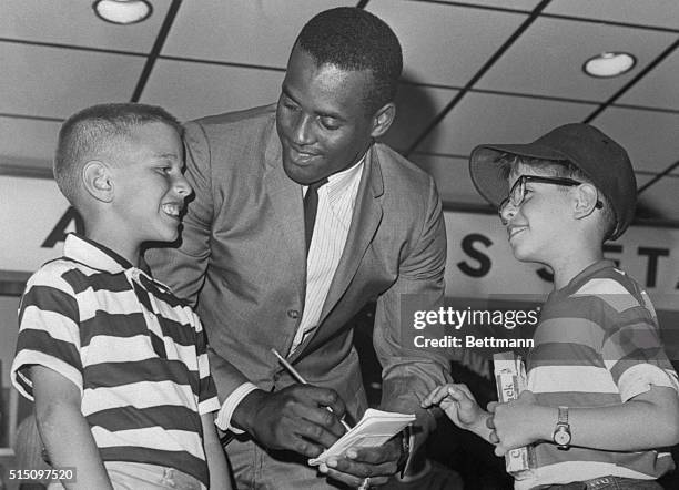 Roberto Clemente, right fielder for the Pittsburgh Pirates, sign autographs for left to right, Johnny Sloan and Alvin Green both of Brooklyn, New...