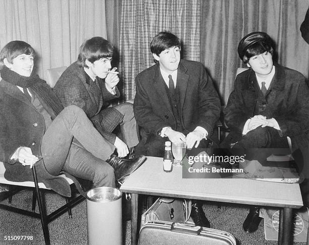 Beatles relaxed...The Beatles, England's top pop quartet enjoy a snack and a smoke at London Airport February 7th, before leaving for their 10-day...