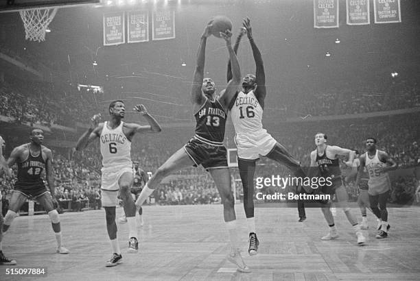 Boston: Wilt Chamberlain of the Warriors' fights for rebound with Tom Sanders of the Celtics' as Bill Russell looks on. Action took place in the...