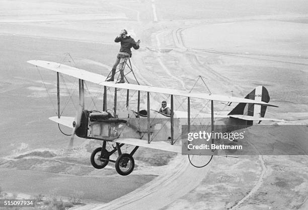 Hollywood: Television comedian Steve Allen waves to fans from precarious perch atop a 1916 Flying Jennie biplane for a film strip which will be shown...