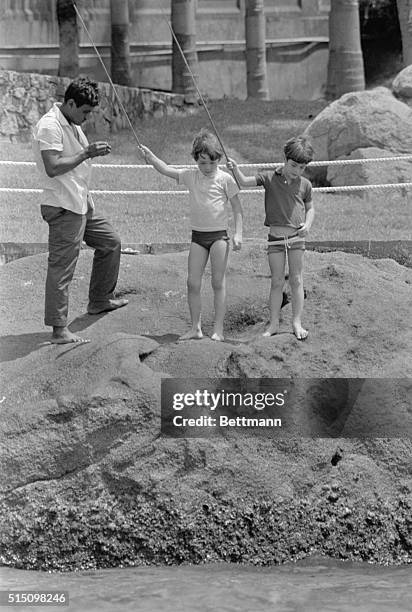 Servant baits hook as John F. Kennedy Jr. And his cousin Anthony Radziwill, fish in the Pacific Ocean. Jacqueline Kennedy and her sister, Princess...