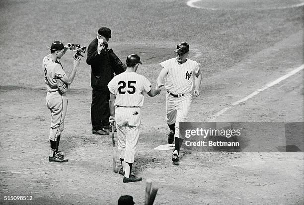 Roger Maris of the New York Yankees in greeted by teammate Joe Papitone as he crosses home plate after hitting his 13th home run in 6th inning of...