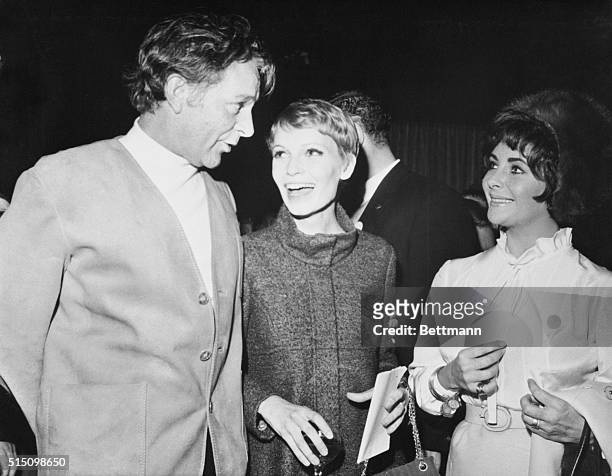 Mia Farrow, wife of Frank Sinatra, enjoys a joke with actor Richard Burton and his wife, actress Elizabeth Taylor, here. The Burton's were scheduled...