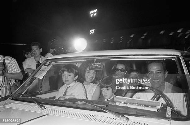 Mrs. John F. Kennedy and her sister, princess Lee Radziwill sit in car with their children following their arrival, at this jet set resort early...