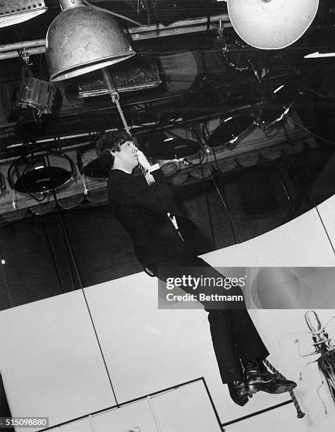 Mop violence...Getting "away from it all," Beatle Paul McCartney gazes wistfully into space while dangling from a stage rope on the set of United...