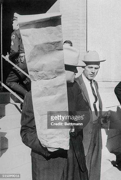 Investigators carry a paper sack believed to have been used to carry Lee Oswald's rifle into the Texas School Book Depository.
