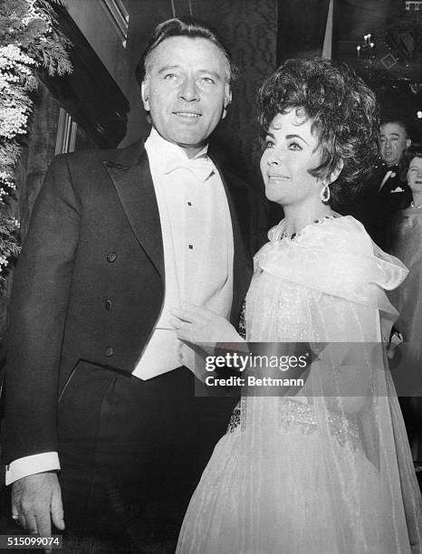 Actor Richard Burton and his wife, actress Elizabeth Taylor beam as they arrive at the Odeon Theater in London for the 1967 Royal Film Performance of...