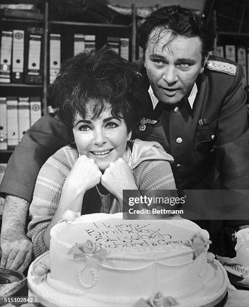Elizabeth Taylor flashes a birthday smile as she and her husband, Richard Burton, pose with a birthday cake given to her on February 27th by her...