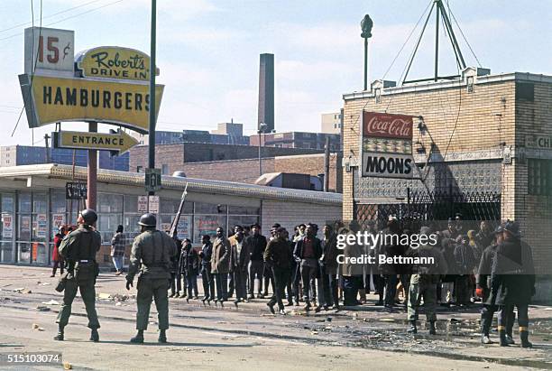 National Guardsman attempt crowd control after riots broke out in Chicago after the assassination of Martin Luther King. To the right, two fireman...