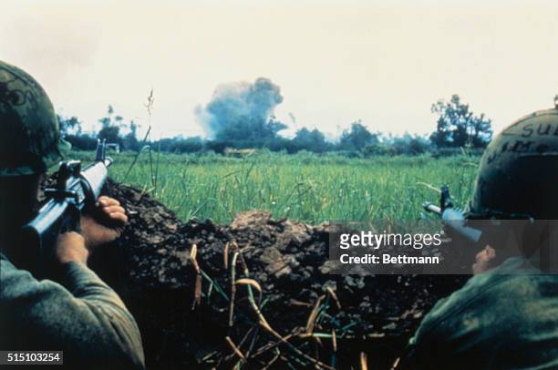 Two U.S. Marines sight in on the Vietcong movement in a fortified enemy hamlet during air strike.