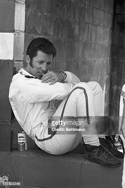 Mario Andretti from Nazareth, Pennsylvania, bites on his thumb as his crew works on his Ferrari 512/s in the pitt. Andretti will drive one of the 70...
