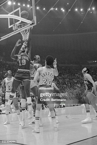 Inglewood, California: Wilt Chamberlain goes up through the basket as he attempts to block a shot by Willis Reed of New York. Reed hit a free throw...