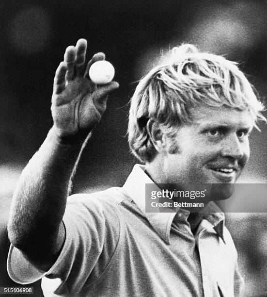 Jack Nicklaus holds the winning ball on the 18th green as he walks away and waves to the gallery on the PGA tour.