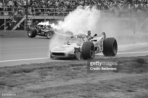 Speedway: Mike Mosley sits in his burning racer after collision on the 4th turn against a retaining wall. In rear is Bobby Unser, also on fire.