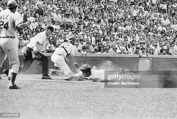 Cincinnati Reds Pete Rose throws up a cloud of dust as he makes a leaping slide at the plate and arrives safely, coming in from second on Hal McRae's...