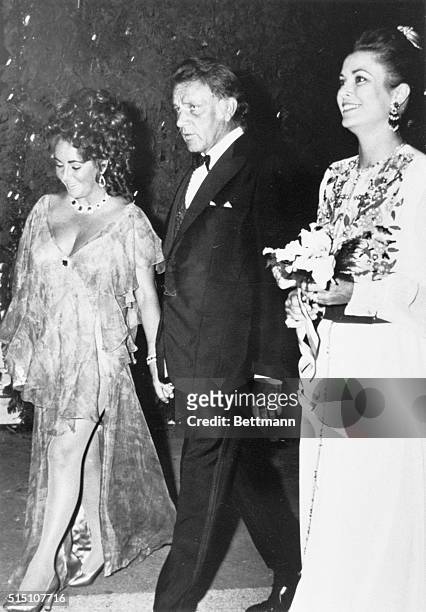 Monaco: Printed chiffon dress for actress Elizabeth Taylor escorted by her actor husband Richard Burton as both are greeted by Princess Grace of...