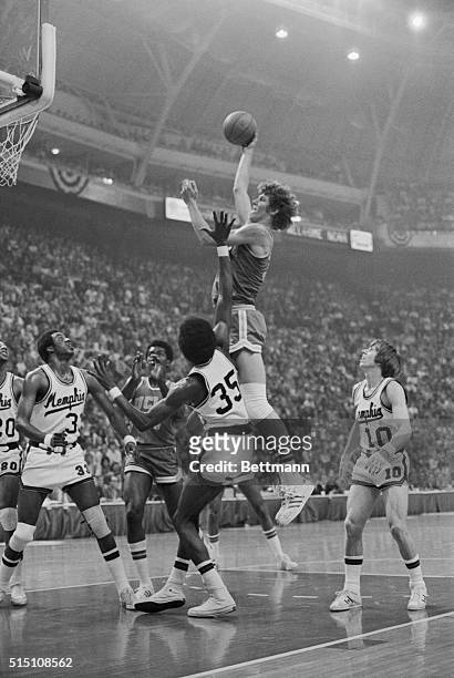 St. Louis: UCLA's 6'11" Bill Walton towers over everyone as he makes a jump shot in the first half of the UCLA-Memphis State NCAA game. Defending for...