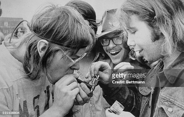 Ann Arbor, Mich.: Lighting a pipe, three young men join in celebrating during Ann Arbor's 2nd Annual Hash Festival on the University of Michigan...