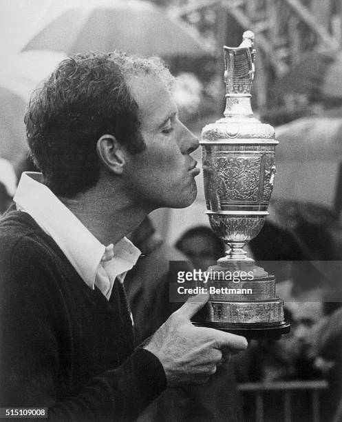 Despite the heavy rainfall, the new British Open Golf Champion Tom Weiskopf kisses the cup after winning the tournament with a total score of 276, 12...