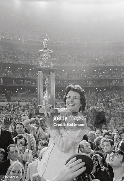 Pro tennis player Billie Jean King holds her newly won trophy high after beating Bobby Riggs in their $100,000 winner-take-all "Battle of the Sexes"...