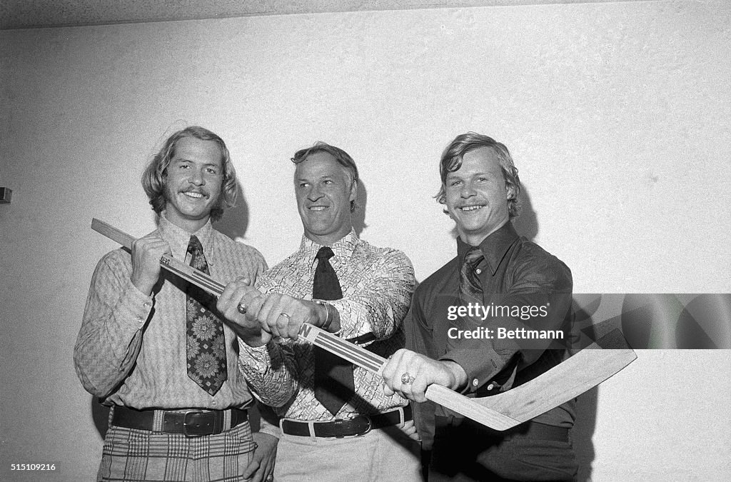 Gordon Howe Holds Hockey Stick With Sons