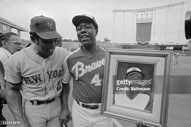 Willie Mays of the New York Mets and Hank Aaron of the Atlanta Braves joke about a picture of Aaron which was presented to him at a workout for the...