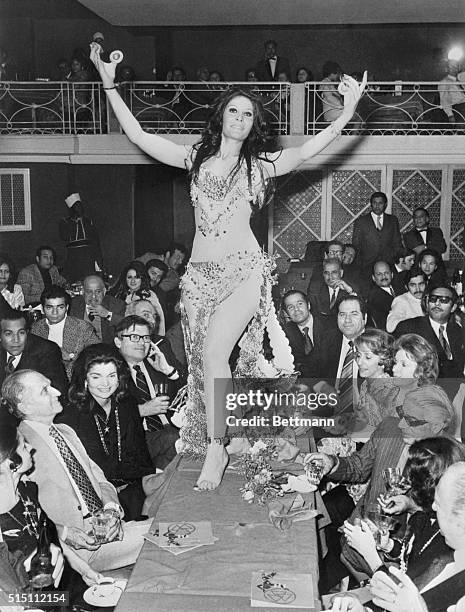 Belly dancer Zizi Mostafa provides after dinner entertainment for Mrs. Jacqueline Kennedy Onassis, , and her husband, Greek shipping millionaire...