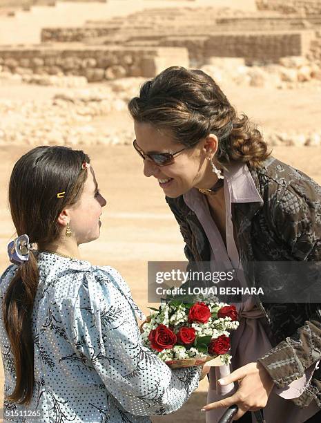 Syria's First Lady Asma al-Assad receives flowers from a young girl during a tour of the historic Syrian city of Ebla, 300 kms north of Damascus, 20...