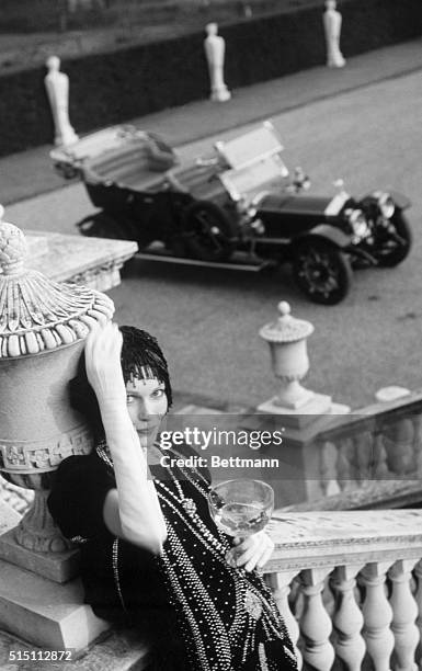 Actress Mia Farrow, playin Daisy Buchanan, drinks some wine while relaxing between takes during the filming of "The Great Gatsby." Undated publicity...