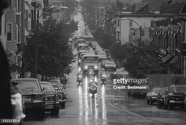 Their headlights reflecting off the wet road due to heavy rain in Boston 10/16, police motorcycle escort lead the school buses with Black students to...