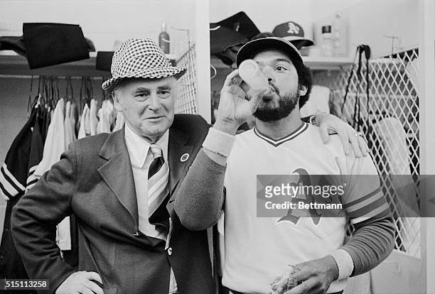 Oakland Athletics owner Charles Finley beams, as his right fielder Reggie Jackson enjoys a bottle of pop in the A's dressing room, after the A's...
