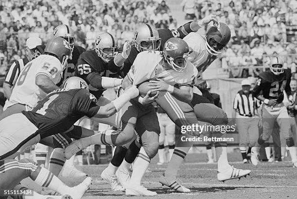 Oakland Raiders linebacker Phil Villapiano grabs hold of Kansas City Chiefs running back Ed Podolak's jersey as other Raiders Dan Conners and Art...