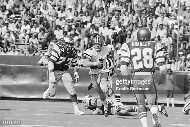 New Orleans Saints' quarterback Archie Manning eludes Philadelphia Eagles' defensive tackles, picking up a first down during a game at Tulane Stadium...