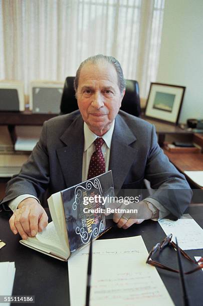 Mortimer Adler, philosopher, who edited for the Encyclopedia Britannica, flips through a book in his office.