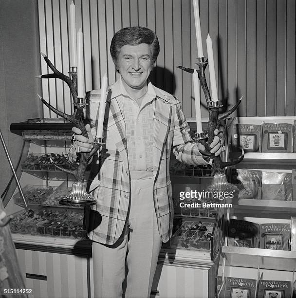 Liberace, famous flamboyant pianist, admires a pair of one-of-a-kind candelabra made out of German north woods reindeer antlers mounted on silver...