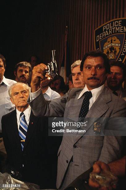 Arresting officer, Detective Edward Zigo, holds up .44 caliber revolver at a press conference in New York after the arrest of a suspect in the Son of...